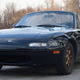 A 1993 black Mazda Miata stopped atop a hill